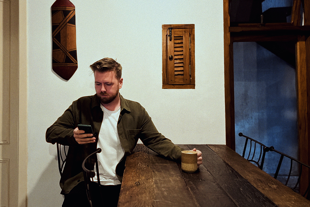 Man drinking coffee whilst scrolling on his phone 